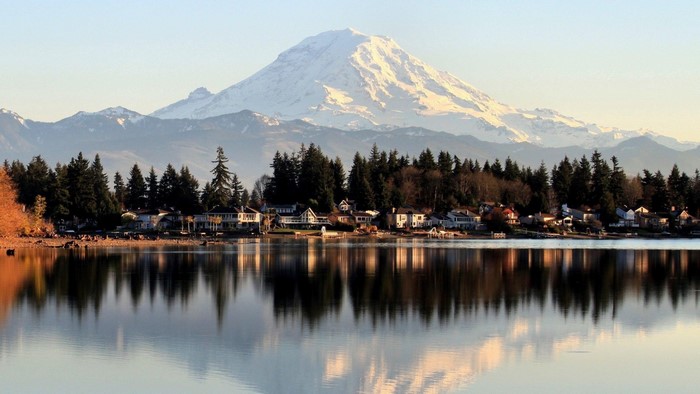 Snow-capped mountain reflected in a lake with houses and trees