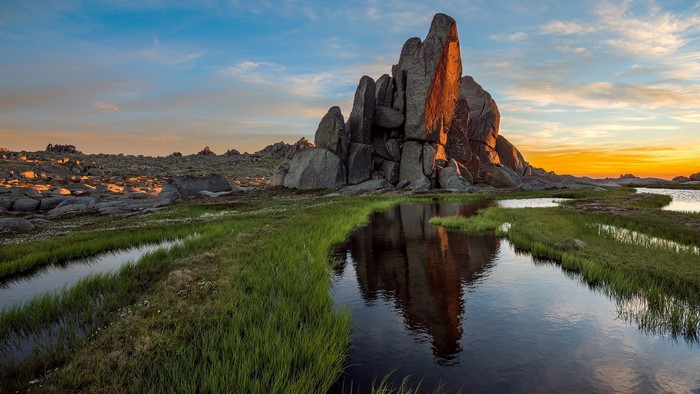Rocky outcrop with water and grass at sunset