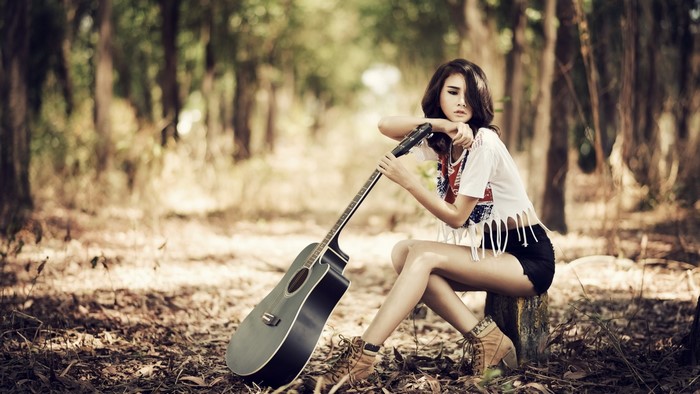 Asian girl with guitar in forest