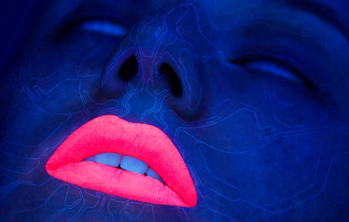 Close-up of a face with neon pink lips under blue light