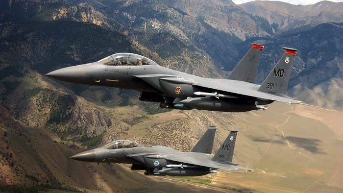 Two F-15 Eagles flying over mountains