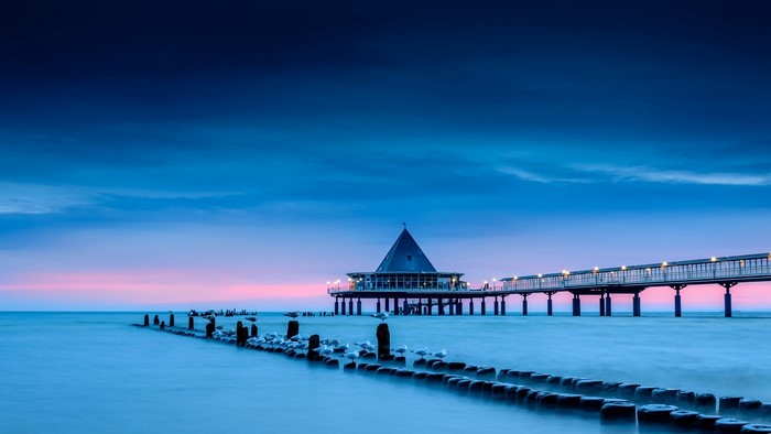 Blue sea pier with lights at dusk