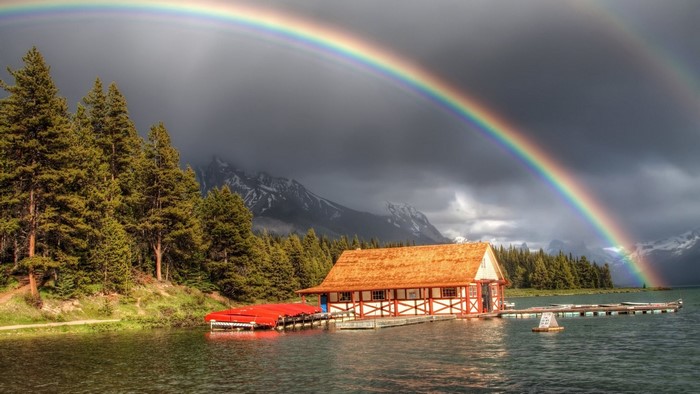 Double rainbow over a lake house with canoes