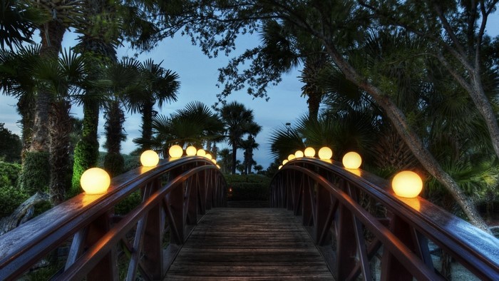 Wooden bridge with illuminated spheres at dusk