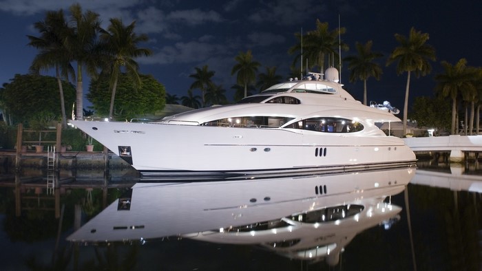 White yacht docked at night with palm trees