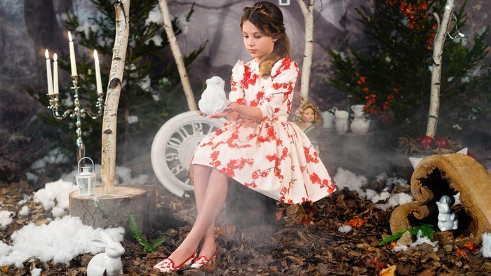 Girl in floral dress holding a white rabbit figurine