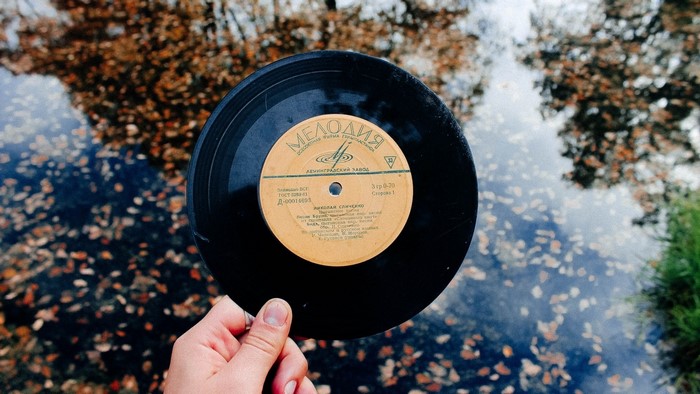 Hand holding a Melodiya vinyl record over water