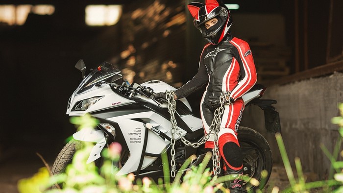 Woman in cat-ear helmet and motorcycle gear with chains