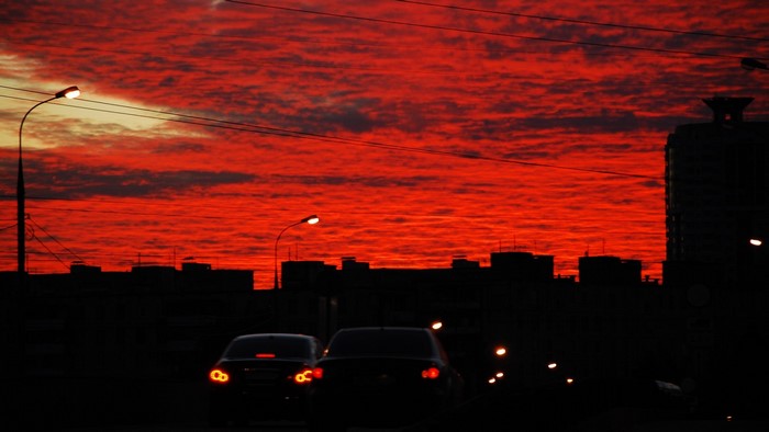 Fiery sunset over city skyline with cars