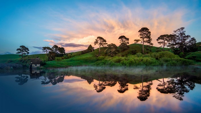 Hobbiton house reflected in a misty lake at sunrise