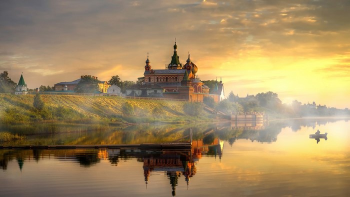 Monastery on a hill reflected in a lake at sunrise