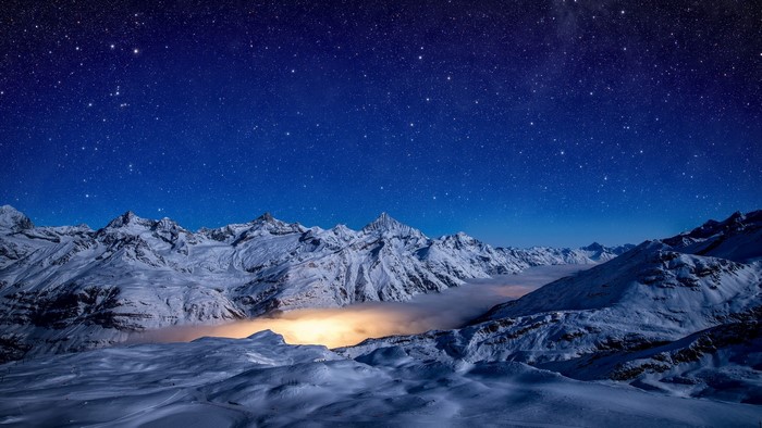 Snowy mountains under a starry night sky