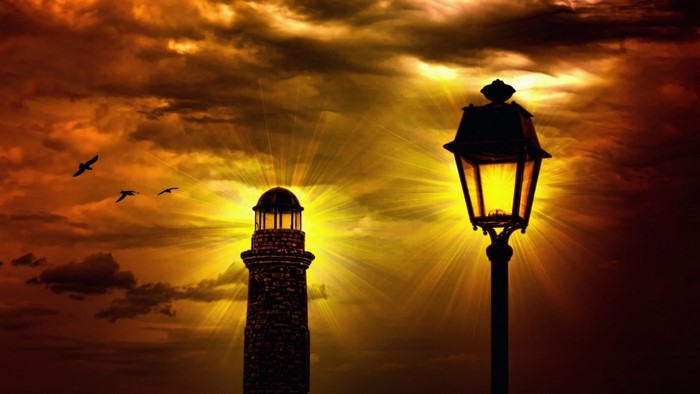 Lighthouse and street lamp with birds at sunset