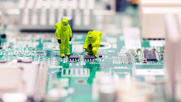 Miniature engineers in hazmat suits on a motherboard