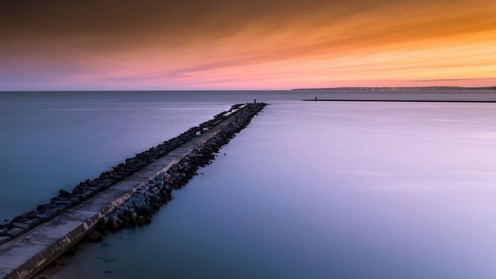 Jetty with lighthouse at sunset