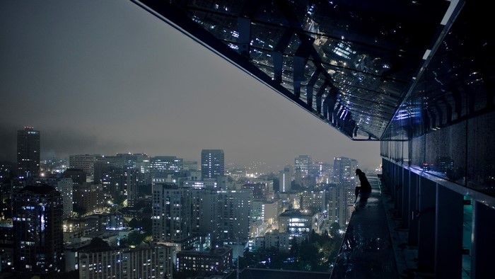 Person on a ledge overlooking a cityscape at night