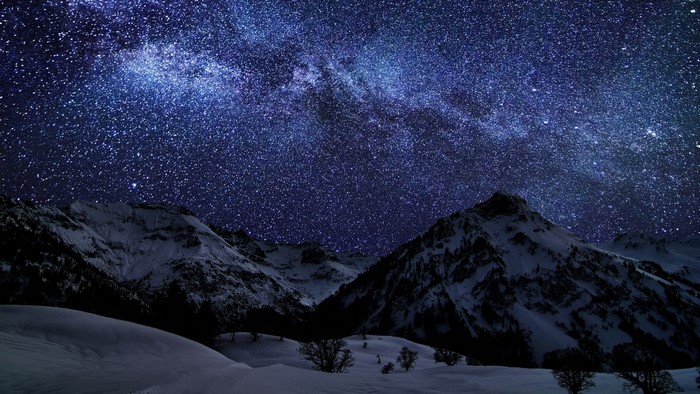Starry night sky over snow-covered mountains