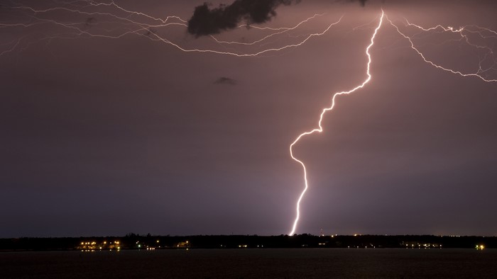 Lightning strike over a dark landscape at night
