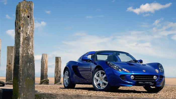 Blue Lotus Elise car on a beach with wooden posts