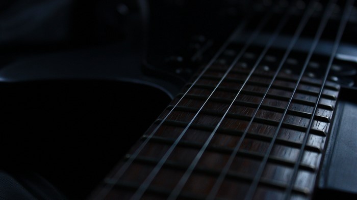 Close-up of a dark electric guitar fretboard and strings