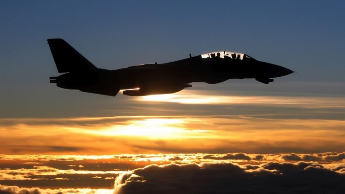 Silhouette of a Navy F-14D Tomcat fighter jet flying at sunset