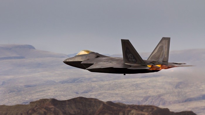 Lockheed Martin F-22 Raptor in flight over desert mountains