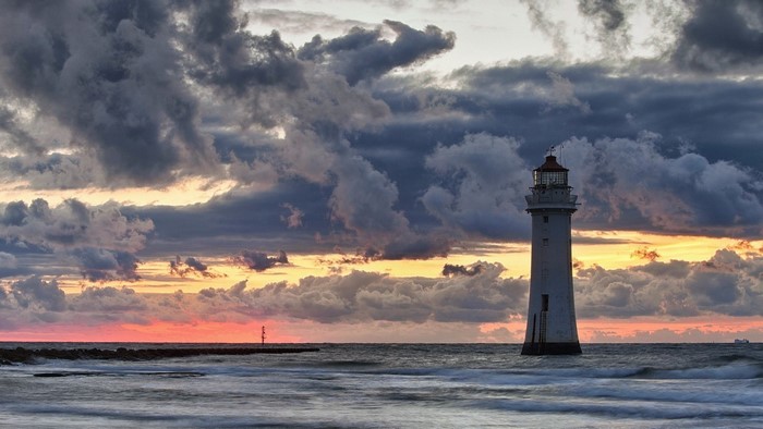 Lighthouse in stormy twilight over the sea