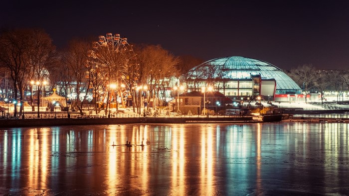 Winter amusement park and dome building by frozen lake at night