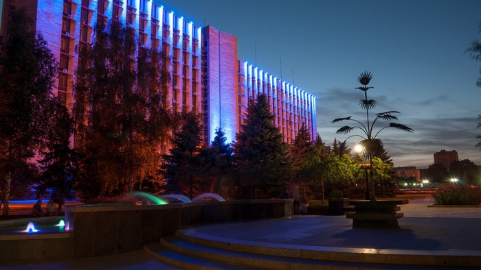 Donetsk building illuminated with blue and orange lights at dusk