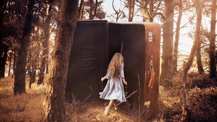 Girl entering a large suitcase in a forest