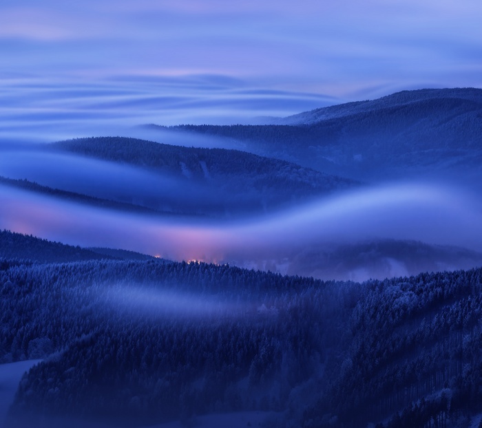 Misty mountains at dawn with distant lights