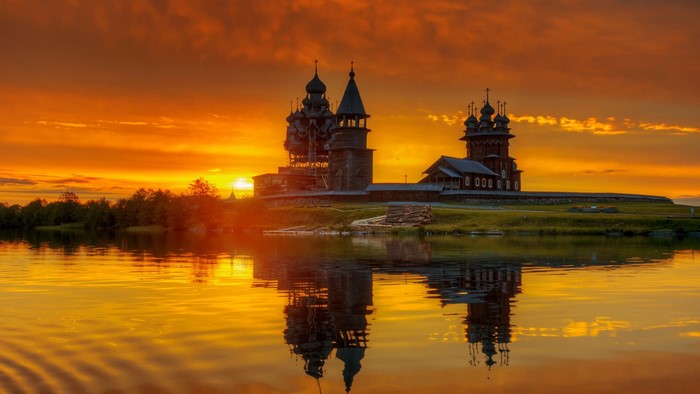 Wooden churches reflected in water at sunset