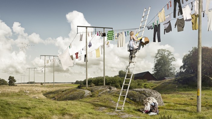 Woman hanging laundry on a clothesline with a ladder