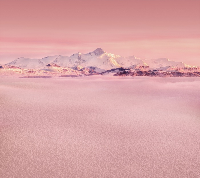 Snowy mountains above pink clouds and snow