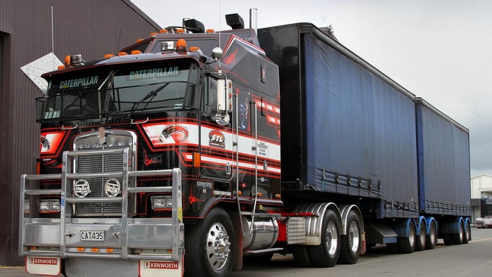 Kenworth truck with Caterpillar branding and blue trailers
