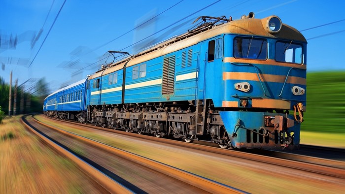 Blue electric train with yellow stripes on tracks