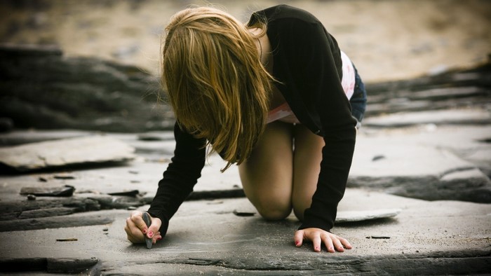 Girl drawing on rocks with chalk