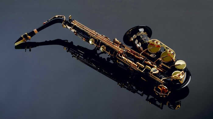 Black and gold saxophone on a reflective surface