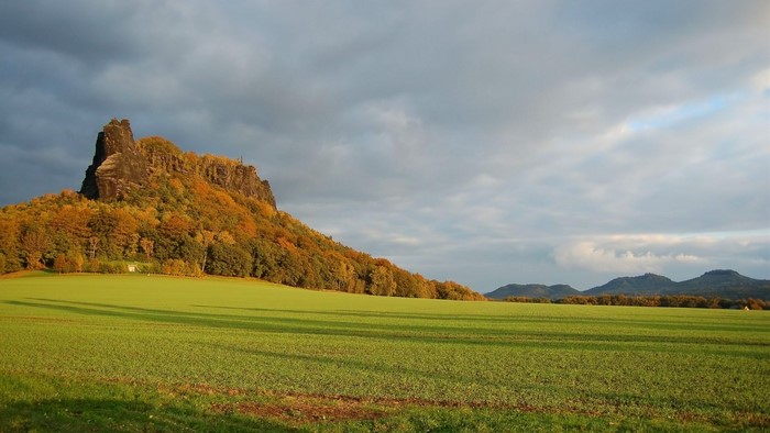 Autumn mountain landscape with green field
