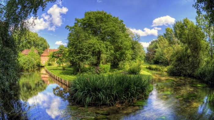 River flowing through a green landscape with trees and a building