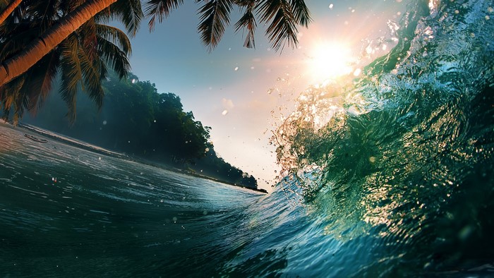 Wave crashing near a tropical island at sunset