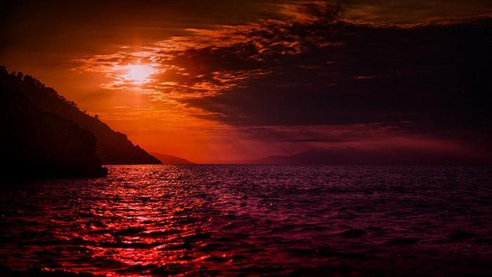 Sunset over the ocean with a mountain silhouette