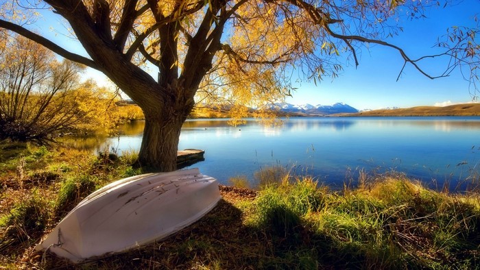 Autumn lake with snow-capped mountains and a boat