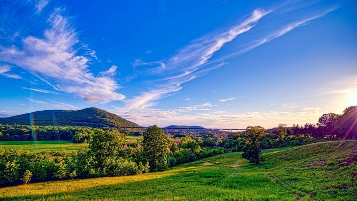 Green Hills and Mountains with a Bridge Under a Blue Sky