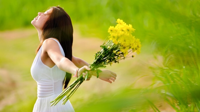 Brunette girl holding yellow flowers in a field