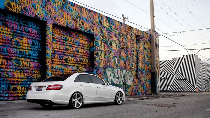 White Mercedes Benz parked by graffiti wall