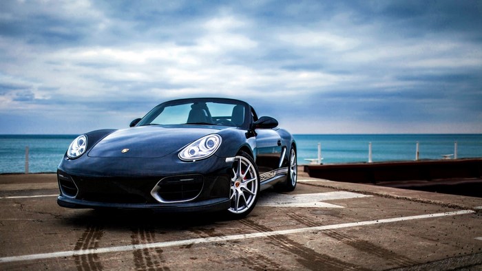 Black Porsche Boxster Spyder convertible by the sea