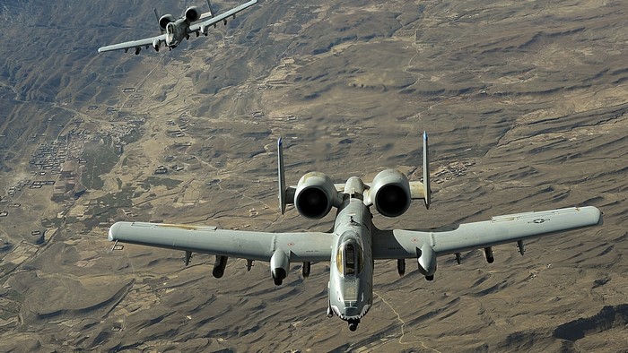 Two A-10 Warthog aircraft flying over a mountainous landscape