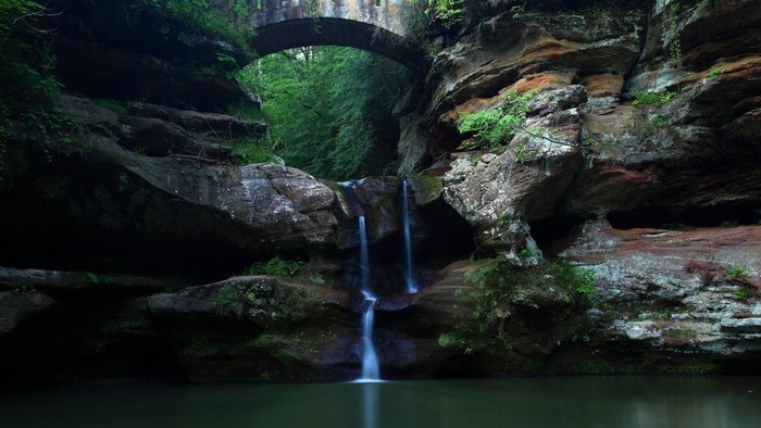 Waterfall flowing under a stone bridge in a forest