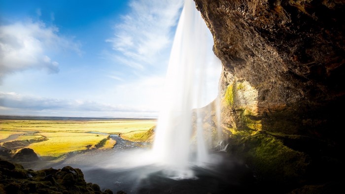 Waterfall in a green valley under a blue sky